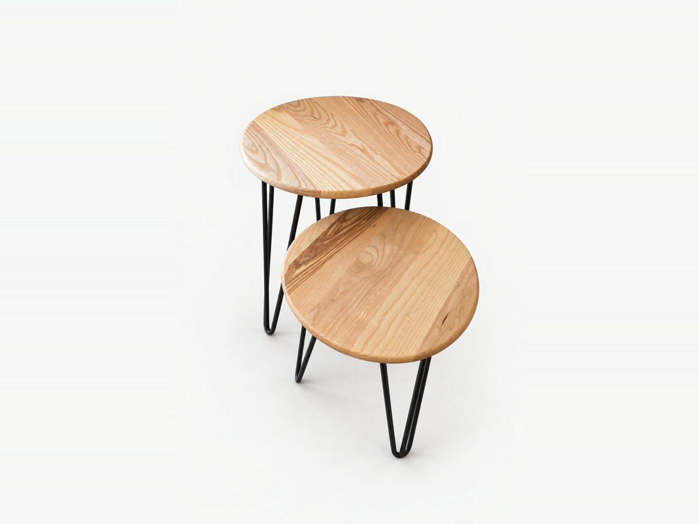 Two round ash side tables on black hairpin legs, one tucked under the other